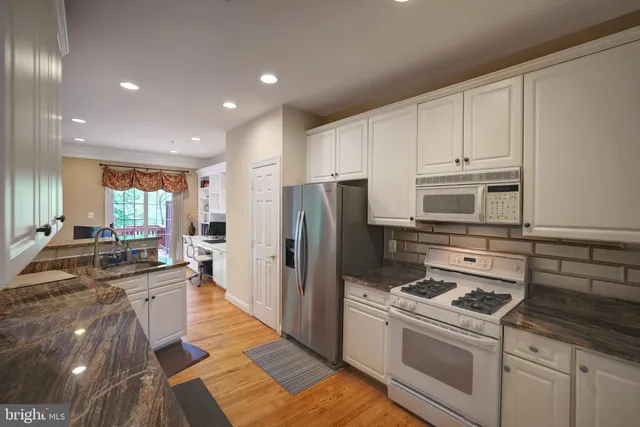 a kitchen with kitchen island granite countertop a sink cabinets and stainless steel appliances