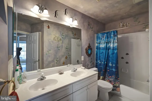 a bathroom with a double vanity sink toilet mirror and shower