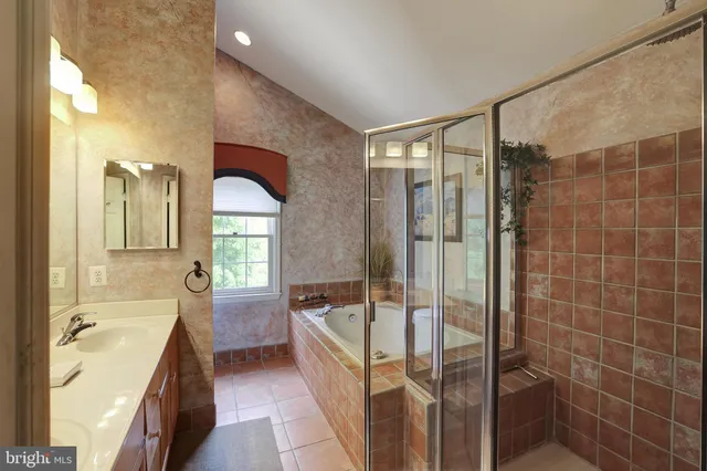 a bathroom with a granite countertop tub sink shower and mirror