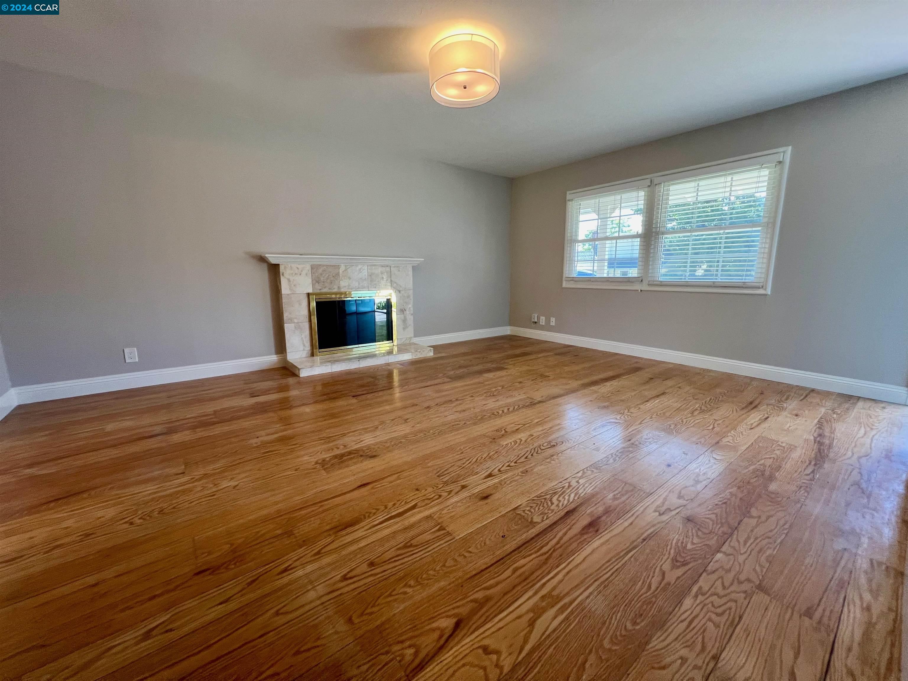 1282 Windermere Way Concord, CA 94521 - Photo 4 of 21 an empty room with wooden floor fireplace and windows