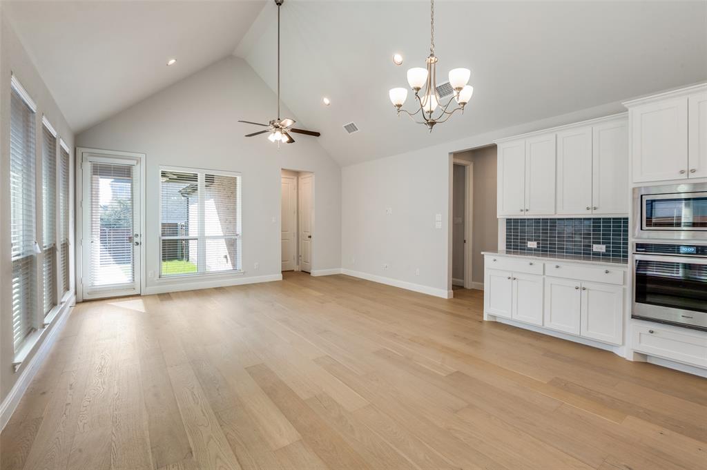 15621 Fringe Tree Road Frisco, TX 75035 - Photo 4 of 18 Kitchen featuring appliances with stainless steel finishes, white cabinetry, high vaulted ceiling, a chandelier, and decorative light fixtures