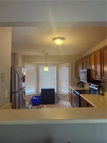 a kitchen with stainless steel appliances granite countertop a refrigerator a stove and a sink with wooden floor