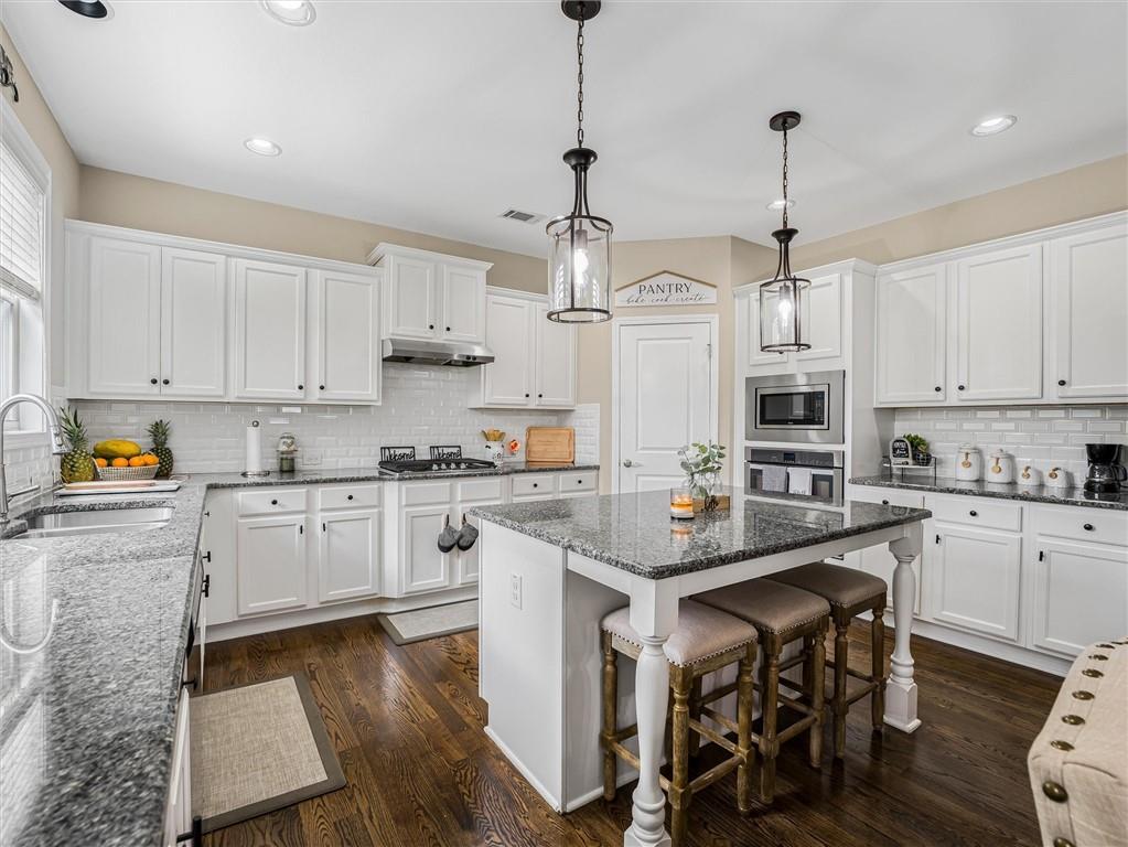 2297 Roberts View Trail Buford, GA 30519 - Photo 16 of 64 a kitchen with stainless steel appliances kitchen island granite countertop a table chairs in it and white cabinets