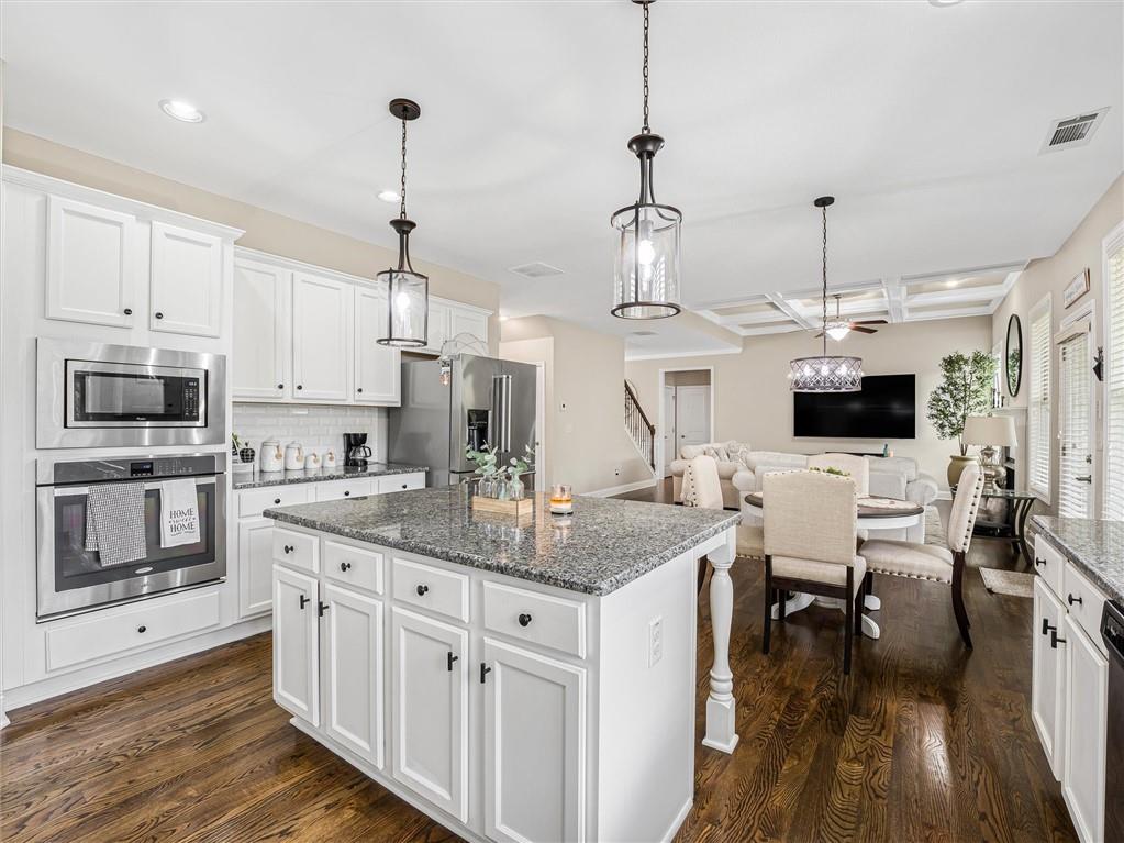 2297 Roberts View Trail Buford, GA 30519 - Photo 20 of 64 a kitchen with stainless steel appliances kitchen island granite countertop a stove a sink and a wooden floor
