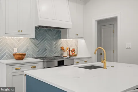 a room with kitchen island granite countertop a sink and wooden floors