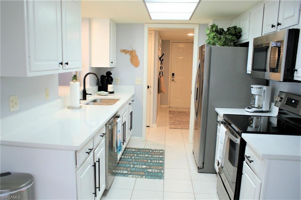 17 Bluebill Avenue, Unit 101 Naples, FL 34108 - Photo 8 of 23 a kitchen with a refrigerator a stove and a sink
