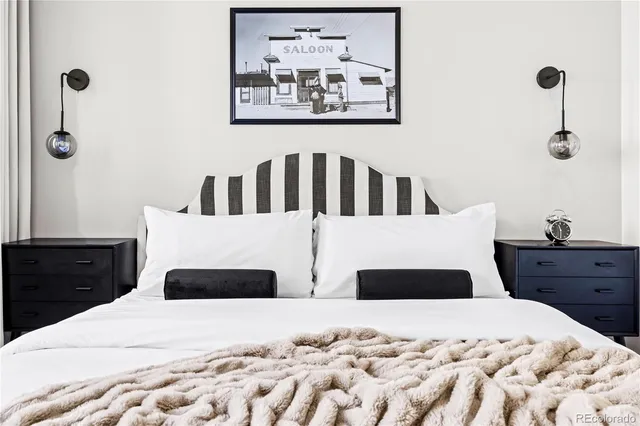 a bedroom with a bed and a lamp on dresser