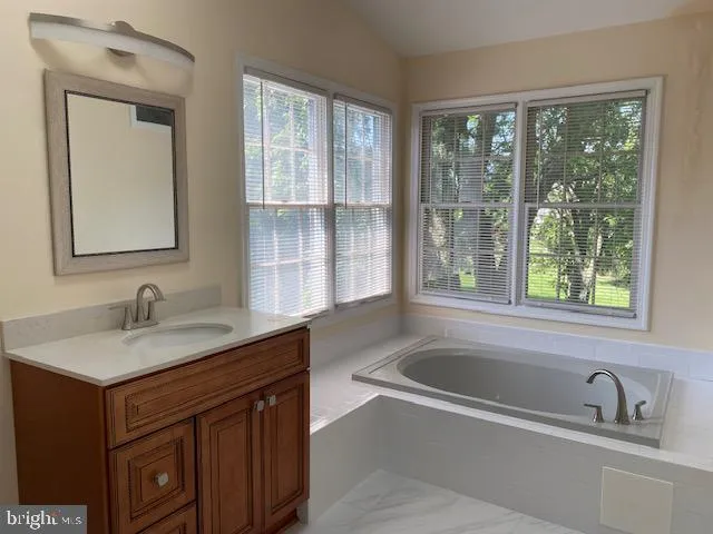 a bathroom with a sink a bathtub and next to a window