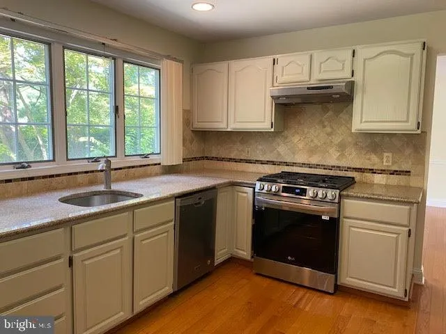 a kitchen with granite countertop a sink stainless steel appliances and window
