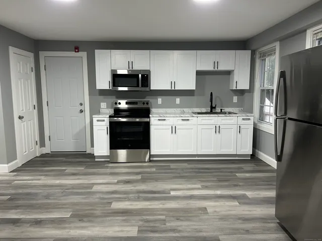 a kitchen with granite countertop a refrigerator stove and sink