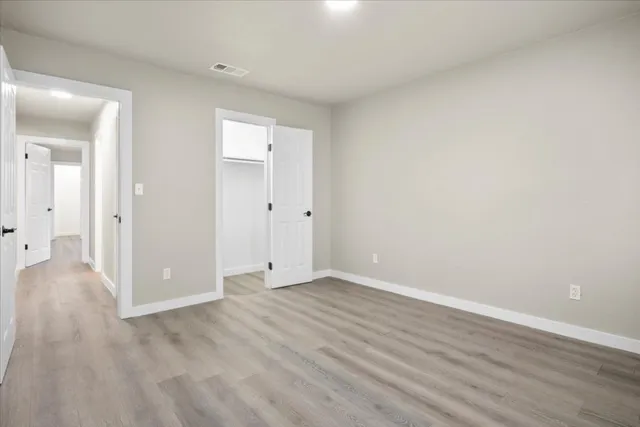 a view of an empty room with wooden floor and closet