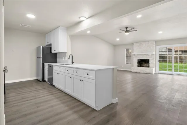 a large white kitchen with a large counter top a sink stainless steel appliances and cabinets