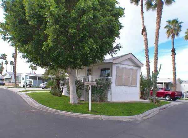 a view of a white house next to a yard and palm trees
