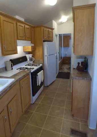 a kitchen with a sink a stove top oven a refrigerator and a window