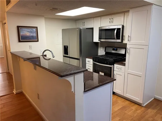 a kitchen with stainless steel appliances granite countertop a refrigerator a stove top oven a sink and dishwasher