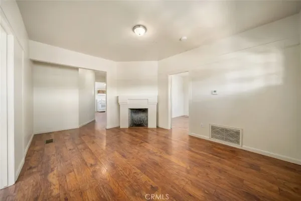 a view of empty room with wooden floor and fireplace