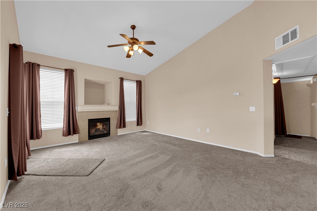 10550 West Alexander Road, Unit 2233 Las Vegas, NV 89129 - Photo 13 of 35 Unfurnished living room featuring a ceiling fan, baseboards, a tiled fireplace, visible vents, and carpet floors