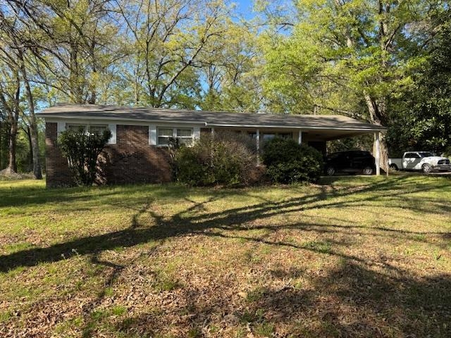 Single story home featuring an attached carport, a front lawn, and brick siding