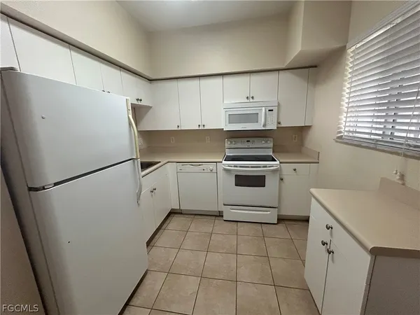 a kitchen with a white cabinets a refrigerator and a stove