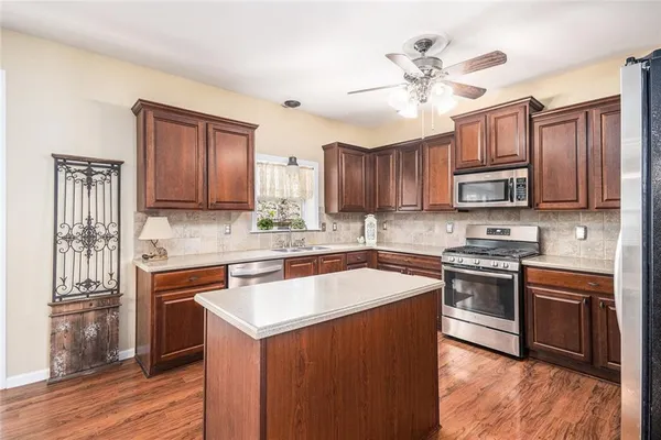 a kitchen with stainless steel appliances granite countertop a stove top oven a sink dishwasher a dining table and chairs with wooden floor