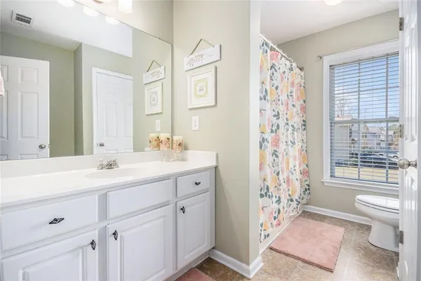 a spacious bathroom with double vanity sink a mirror a toilet a shower and a window