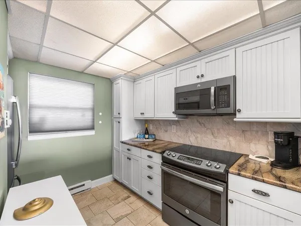 a kitchen with stainless steel appliances granite countertop a sink a stove a microwave oven and white cabinets