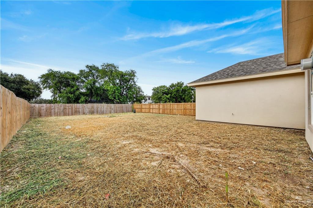 1920 Trinity Street Donna, TX 78537 - Photo 20 of 23 Spacious backyard featuring a new wood privacy fence, substantial open area, and a neutral-toned exterior wall