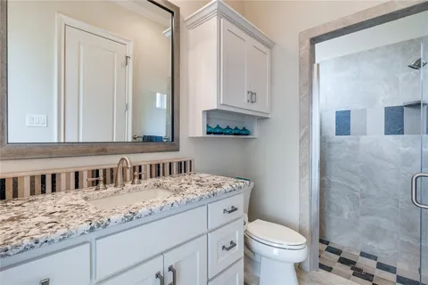 a bathroom with a granite countertop sink a toilet and a mirror