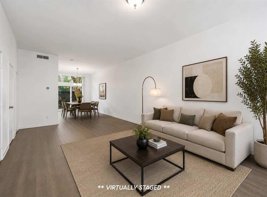 2815 Welborn Street, Unit 101 Dallas, TX 75219 - Photo 13 of 29 Open-concept living area featuring wood-finish flooring throughout, a dining space with natural light, a window overlooking exterior greenery, and clean white walls