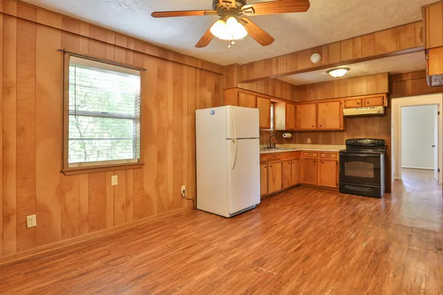 a kitchen with kitchen island wooden floors appliances and cabinets