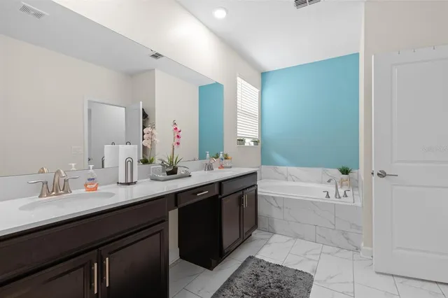 a bathroom with a tub a sink double and mirror