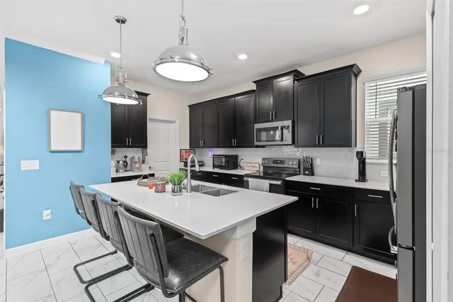 a kitchen with stainless steel appliances a sink a stove a refrigerator and cabinets