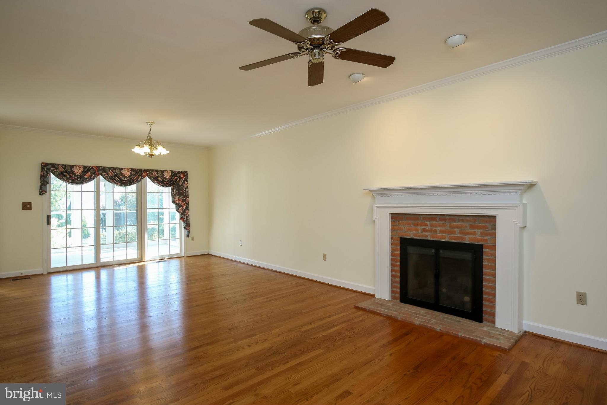 2446 Five Shillings Road Frederick, MD 21701 - Photo 6 of 30 a view of an empty room with wooden floor fireplace and a window