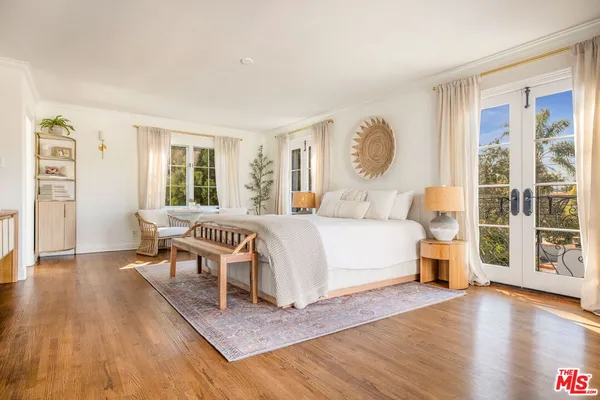 a spacious bedroom with a balcony a bed and a flat screen tv