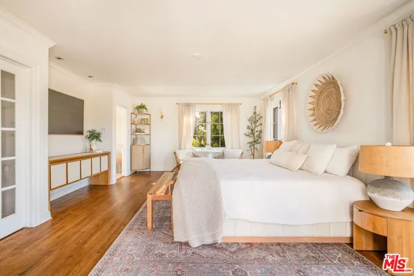 a bedroom with a large bed and a wooden floor