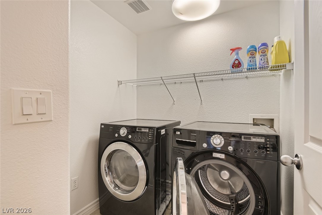 7701 West Robindale Road, Unit 265 Las Vegas, NV 89113 - Photo 24 of 27 A dedicated laundry space is equipped with modern side-by-side machines and overhead wire shelving.