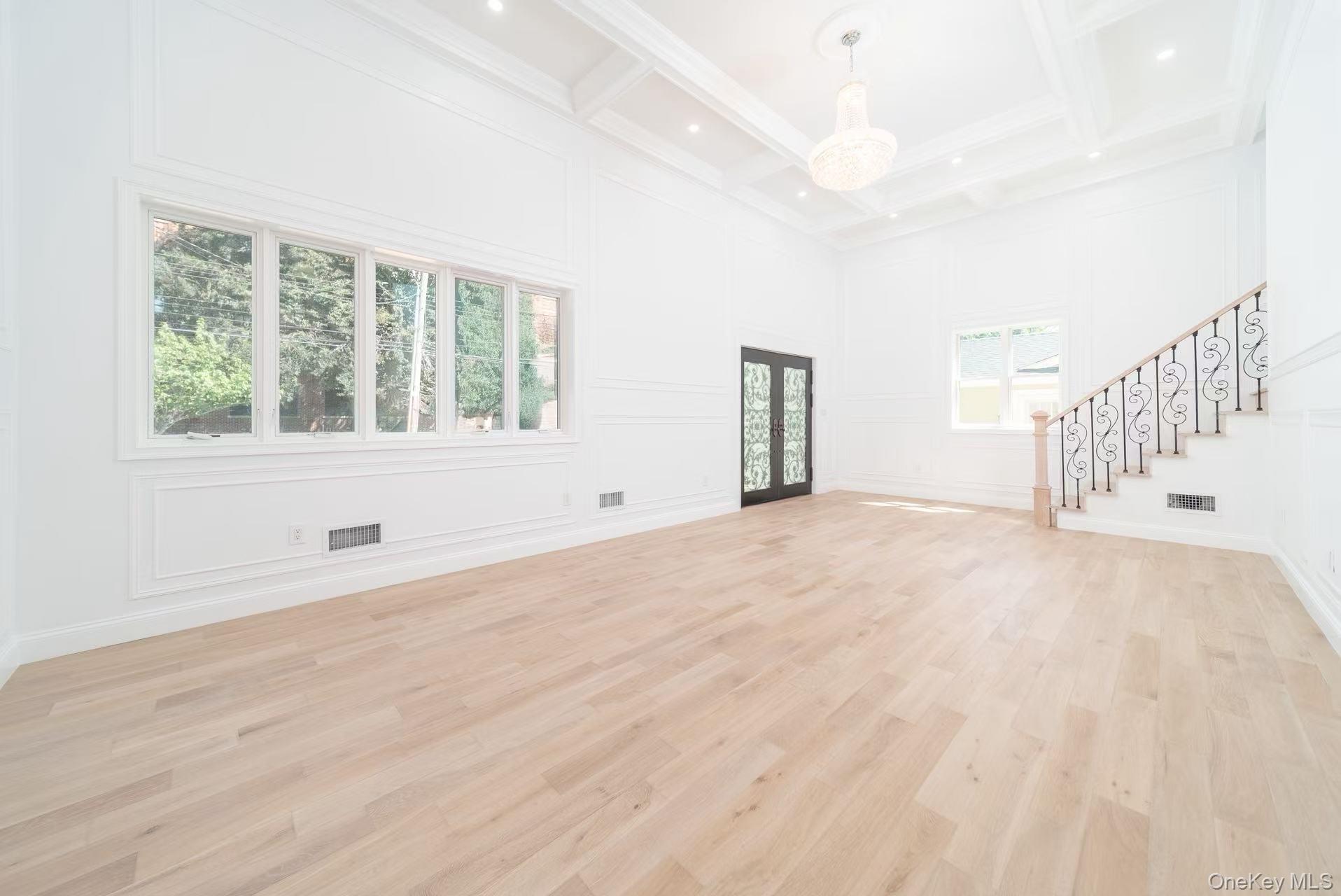 7-24 128th Street Queens, NY 11356 - Photo 14 of 31 Unfurnished living room with light wood-style floors, stairway, a decorative wall, beam ceiling, and coffered ceiling