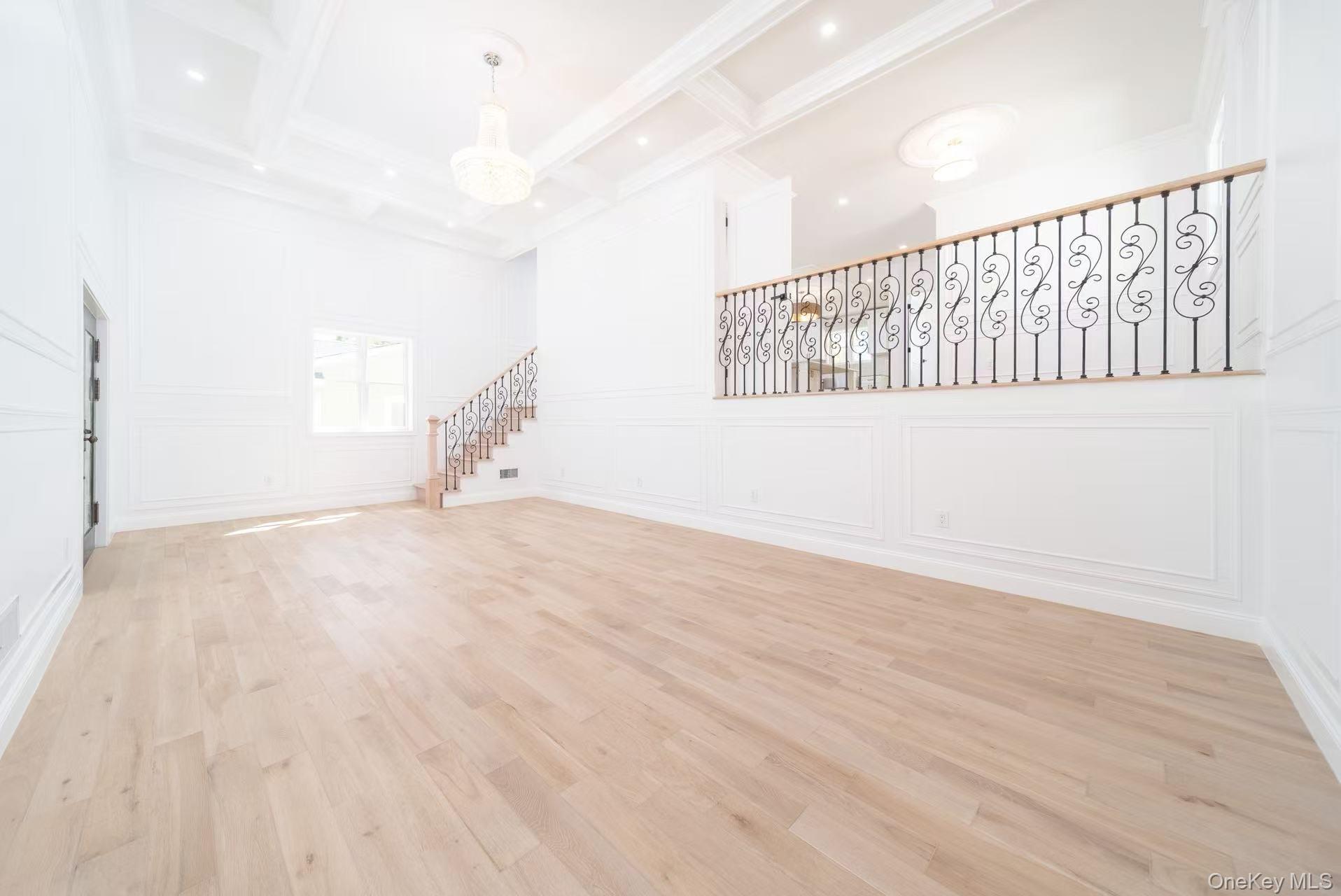 7-24 128th Street Queens, NY 11356 - Photo 15 of 31 Empty room featuring a decorative wall, stairway, light wood-style flooring, beamed ceiling, and coffered ceiling