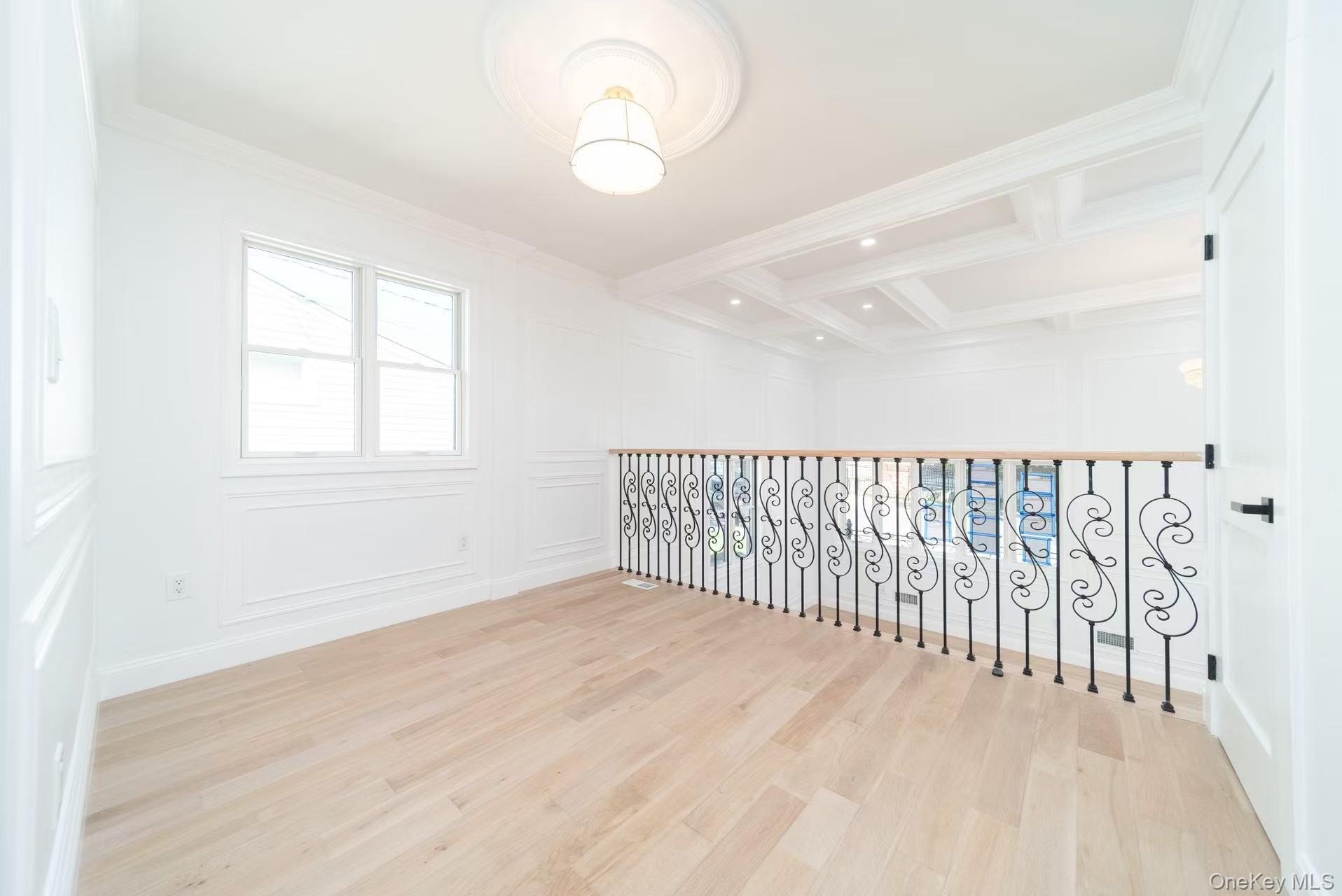 7-24 128th Street Queens, NY 11356 - Photo 18 of 31 Empty room with light wood-type flooring, a decorative wall, beam ceiling, coffered ceiling, and ornamental molding