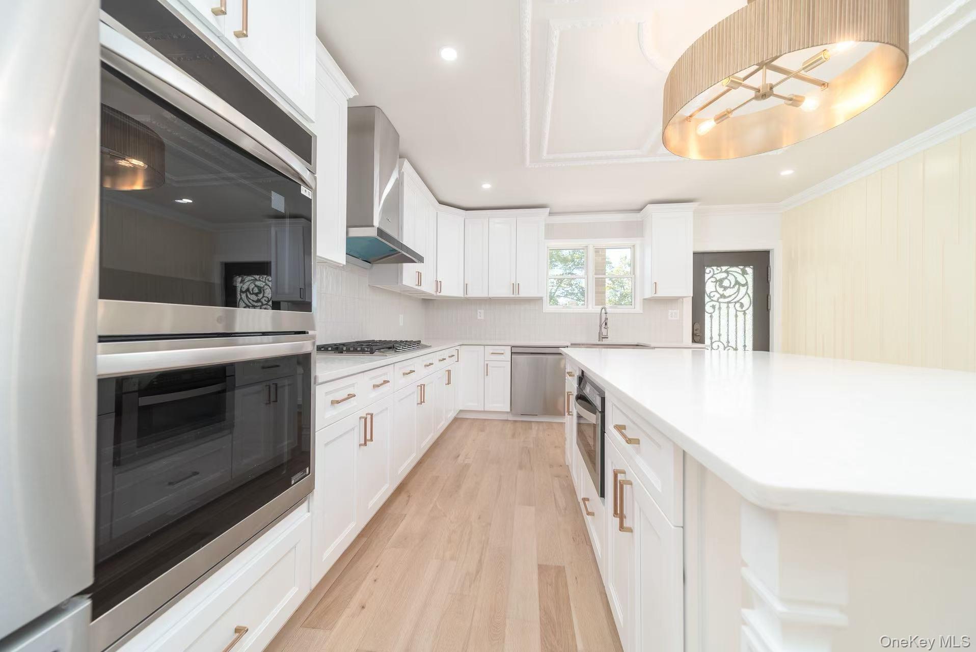 7-24 128th Street Queens, NY 11356 - Photo 5 of 31 Kitchen featuring appliances with stainless steel finishes, recessed lighting, white cabinets, light wood-type flooring, and decorative backsplash