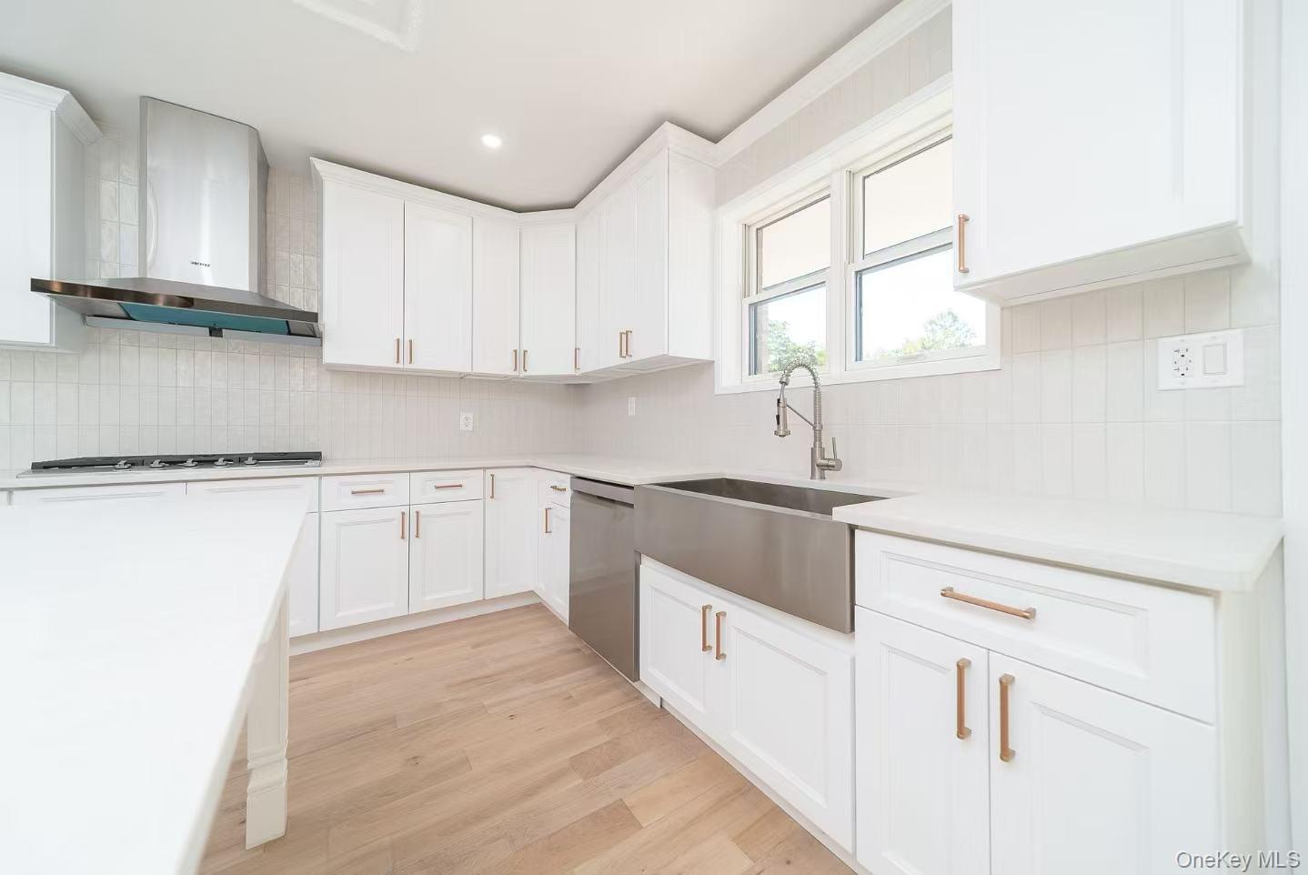 7-24 128th Street Queens, NY 11356 - Photo 6 of 31 Kitchen featuring decorative backsplash, wall chimney range hood, light wood finished floors, white cabinetry, and dishwasher