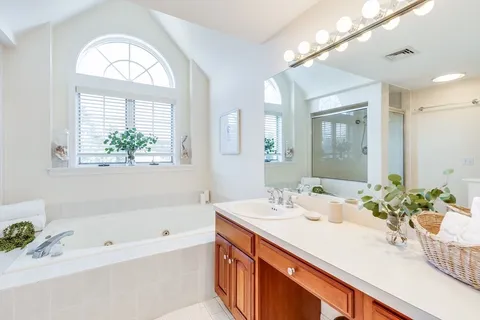 a bathroom with a tub a sink and a large mirror