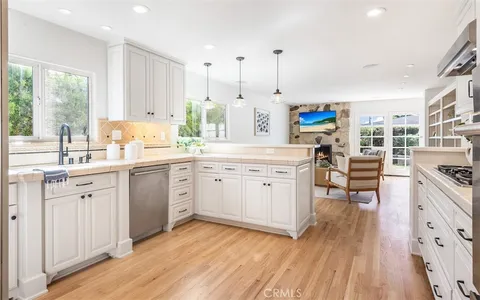 a kitchen with stainless steel appliances sink stove and wooden floor