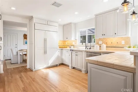 a kitchen with a sink a stove a refrigerator and white cabinets