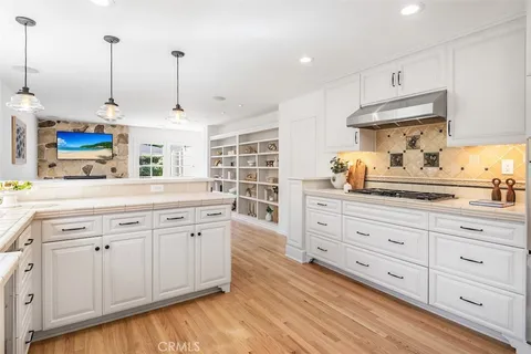 a kitchen with stainless steel appliances granite countertop a sink a stove and a wooden floors