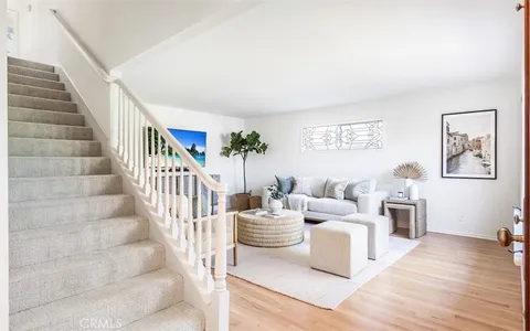 a living room with furniture and a dining table with wooden floor