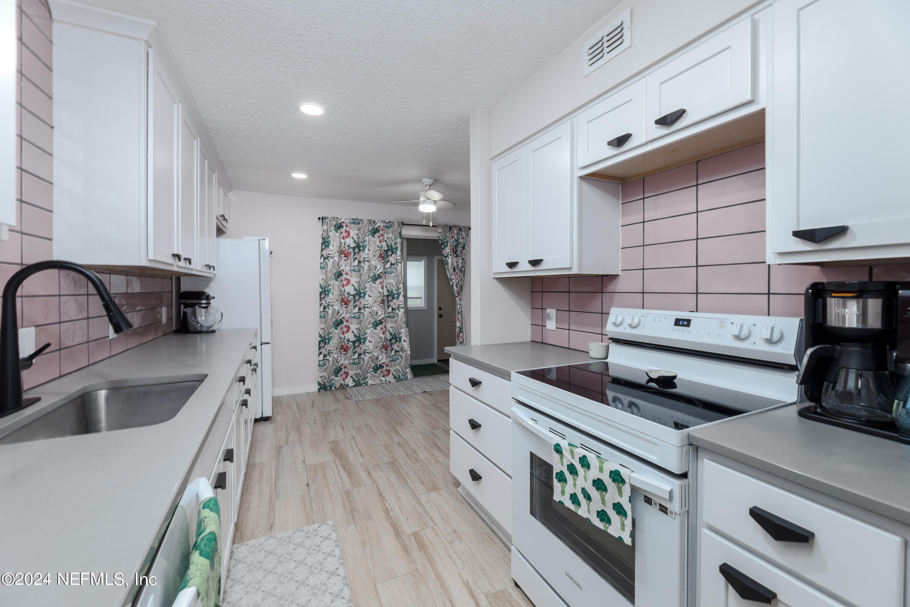 824 Cavalla Road Atlantic Beach, FL 32233 - Photo 7 of 18 a kitchen with kitchen island a stove a sink and white cabinets