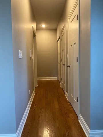 a view of a hallway with wooden floor and a bathroom