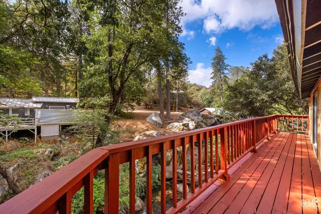 a balcony with wooden floor and trees in the back