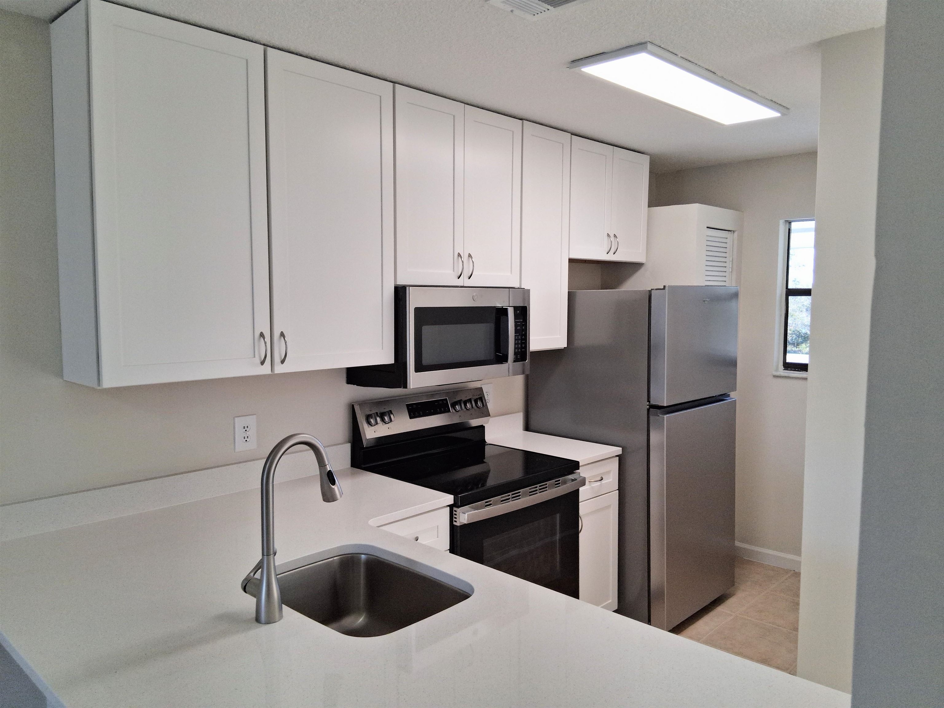 700 West Pope Road, Unit G50 St. Augustine, FL 32080 - Photo 4 of 10 Kitchen with electric stove, white cabinets, light tile patterned floors, and light stone countertops